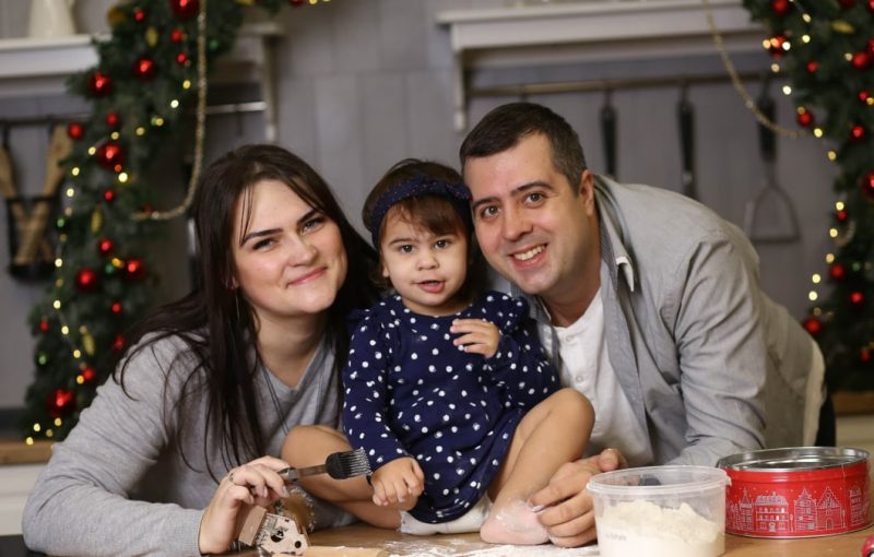 Happy family baking Christmas cookies together in a decorated kitchen.